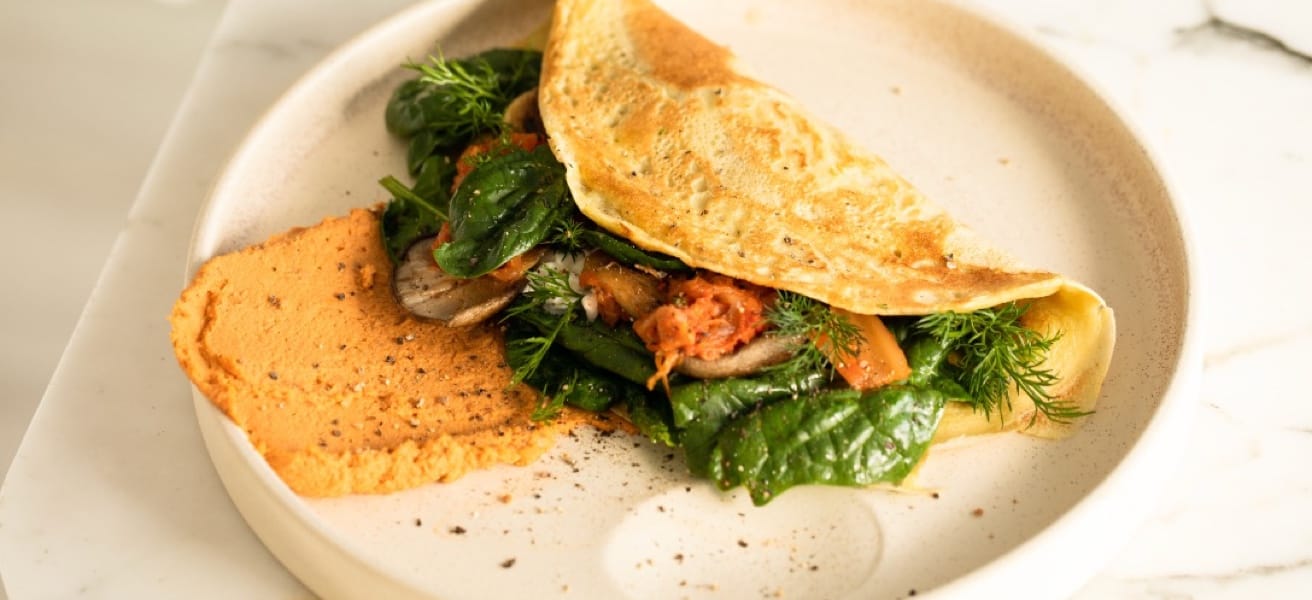 A close up picutre of an omelette on a white plate ready to be served.